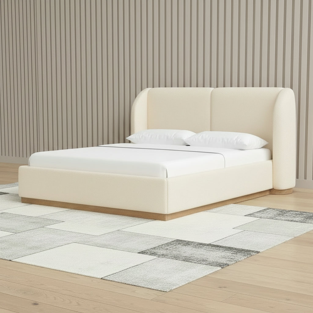 Beige upholstered bed with white bedding in a room with striped wallpaper and a checkered rug.